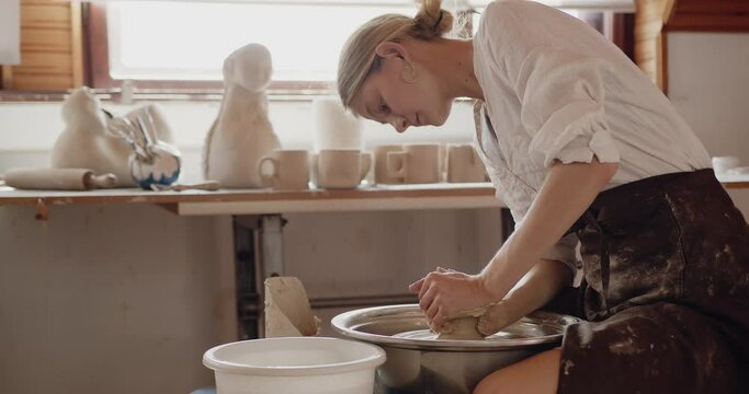 Girl potter making ceramic pot on the twisted pottery wheel