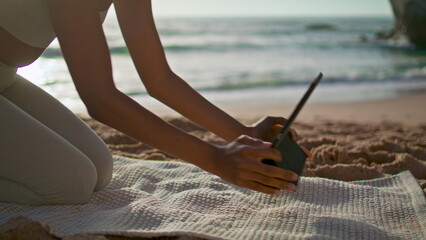 Girl putting tablet yoga mat lying sand beach close up. Woman preparing training