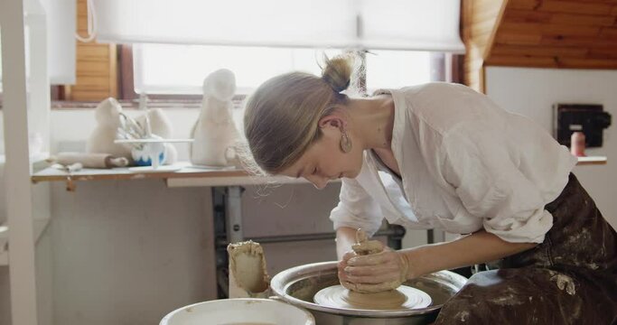Woman potter makes a pitcher out of clay, handicraft, production of handmade tableware