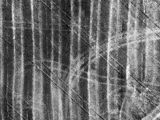 Aerial drone background view of brown rural agricultural field with a lot of car or vehicle tracks. Harvested crops with visible stubble. Image contain noise and blur. Black and white image