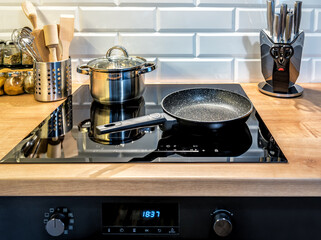 Steel cooking pot and pan on induction hob in modern kitchen