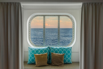 Blick durch das Kabinenfenster eines Kreuzfahrtschiffs bei Abendstimmung	

