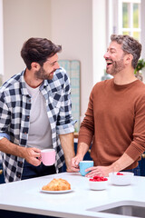 Same Sex Male Couple At Home In Kitchen Having Breakfast Together