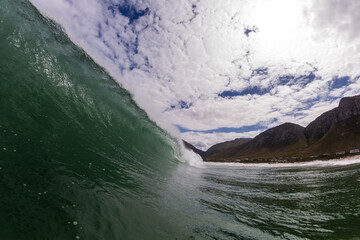 Fototapeta na wymiar huge wave breaking in the ocean with a mountain background