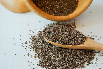 Chia seeds stack and spoon with wooden bowl on white background.