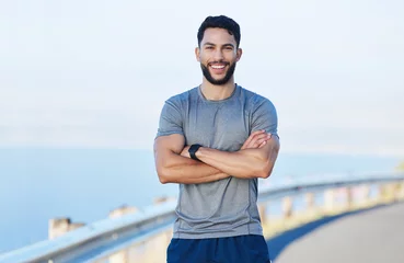 Tuinposter Man athlete, healthy and with cross arms, smile and stand happy outdoor for workout, warm up and wellness..Portrait, confident male and trainer ready for training, fitness and enjoy health exercise. © Wesley J/peopleimages.com