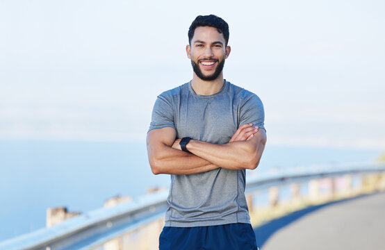 Foto Stock Fitness, exercise and portrait of a sports man standing arms  crossed outdoor with a smile on his face. Workout, health and happy with a  male athlete training outside for cardio