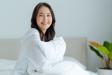 A beautiful woman sitting on a pillow in her bedroom, smiling, laughing happily.