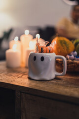 Pareja de tazas de fantasma y calabaza colocadas junto a decoración y golosinas de halloween