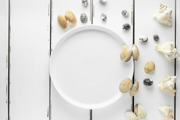 White plate with seashells on white wooding background, wallpaper