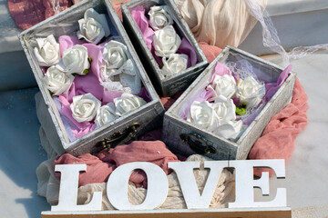  word love on wooden sign and boxes with white flowers in, as  wedding decoration. selective focus