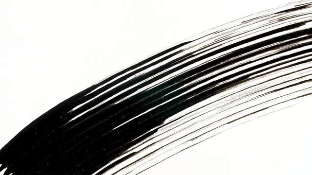 Macro shot and slow motion of a black mascara isolated on white background. Advertising professional cosmetics. Closeup of a mascara wand on white background. High quality 4k footage