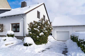 Snow-covered house and garage with icicles on the gutter