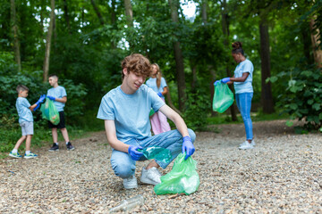 Multiracial group of volunteers taking care of nature ecology and picking garbage in plastic bags...
