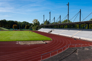 View of the empty stands of the stadium with a green field and a running track.