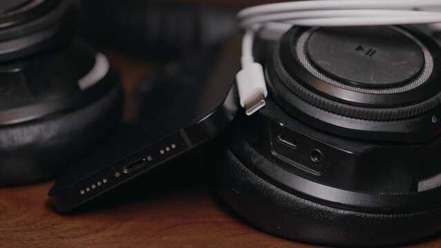 A usb-c charging cable on a desk with wireless head phones and mobile phone