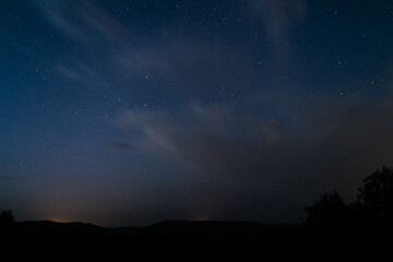 Cielo nocturno con estrellas, nubes y silueta de montañas. Perseidas. 