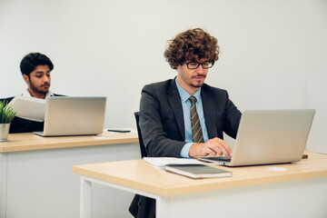 Confident businessman working on laptop at modern office.