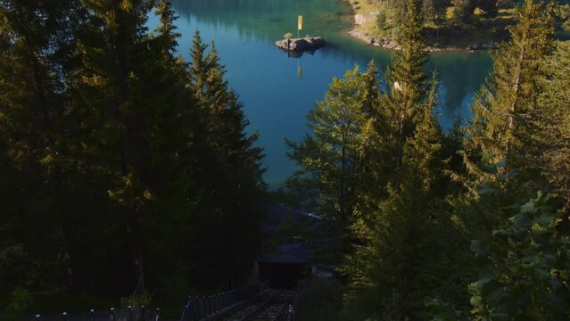 Beautiful Lakefront View from Top of Mountain of Lake Caumasee Switzerland, Lift Railway Facility Towards Turquoise Water Lake Surrounded by Fir and Pine Trees