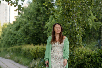 A joyful beautiful young woman among green landscape