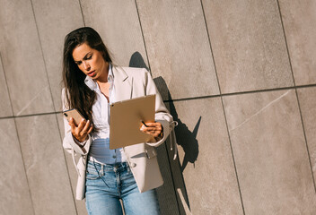 Portrait of a pensive business woman using digital tablet during quick break in front a corporate building.