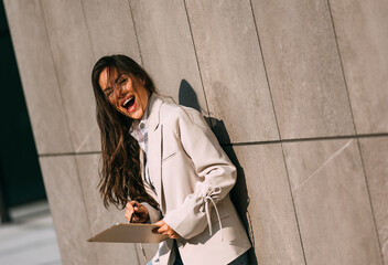 Portrait of a smiling business woman using digital tablet during quick break in front a corporate building.