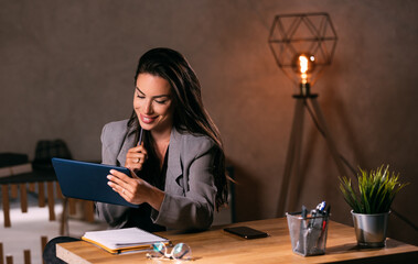 Successful businesswoman stylish using tablet computer at her office at night
