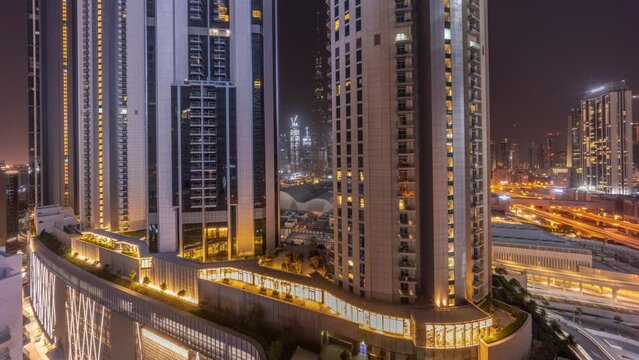Tallest skyscrapers in downtown dubai located on bouleward street near shopping mall aerial timelapse during all night and Moon setting down. Walking area with rooftop gardens