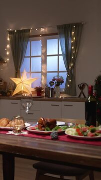 Vertical Screen: luxury dinner in celebration of wedding anniversary in a festive dining room at home with Christmas tree, lights and decors.