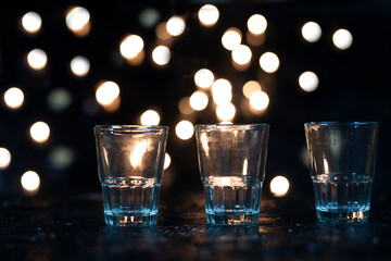 Three shot glasses lined up in a dark area with orange bogies behind them, reminiscent of the festive season