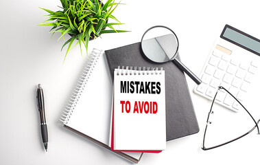 Text MISTAKES TO AVOID on notebook with office tools on white background