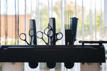 Scissors and combs on a hairdresser's trolley with a window in the background. Copy space.