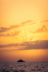 Boat in the distance during a warm summer sunset at the coast of Cyprus