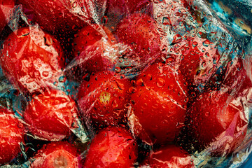 Textured background of freshly picked tomatoes under glass or film with water drops
