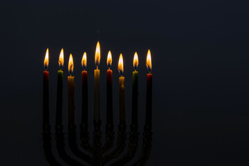 An of Menorah symbols for Jewish holiday Hanukkah festival on black background copy space