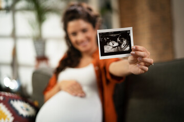 Pregnant woman with ultrasound photo. Beautiful pregnant woman enjoy at home..