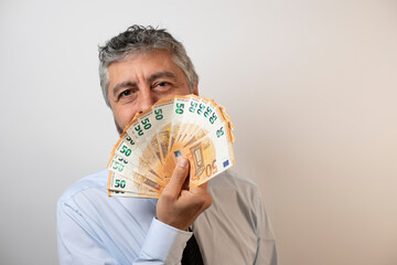 riche homme d'affaires de 50 ans qui joue avec une liasse de billets de banque. Concept du profit, du capitalisme et de l'enrichissement - obrazy, fototapety, plakaty