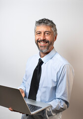 portrait d'un homme d'affaires souriant de 50 ans qui travaille sur un ordinateur portable. Il regarde la caméra