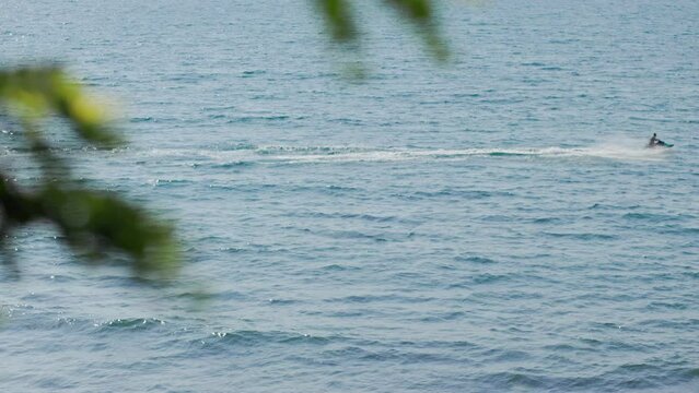 Sea surf in sunny weather, top view. Blue ocean waves. Person swims on a jet ski. Slow motion, copy space.