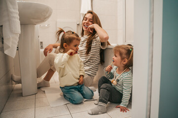 Happy mother observing her children during the tooth-brushing procedure