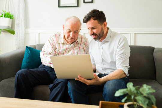Happy son and elderly father using the laptop together