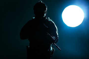 Army soldier in Protective Combat Uniform holding Special Operations Forces Combat Assault Rifle operating at night lit by the moonlight