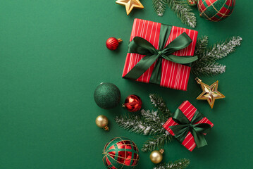 Christmas decorations concept. Top view photo of present boxes with ribbon bows red green and gold baubles star ornaments and pine branches in frost on isolated green background