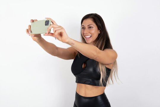 young beautiful woman wearing sportswear over white background taking a selfie to post it on social media or having a video call with friends.