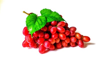 Sweet fruit red grapes with green leaves isolated on white background.