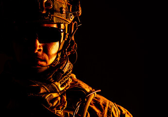 Elite member of US Army ranger in combat helmet and dark glasses. Studio shot, dark black background, looking at camera, dark contrast, toned and colorized