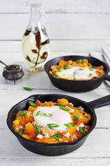 Shakshouka in frying pan. Fried eggs with vegetables, tomato, pepper, pumpkin and onion