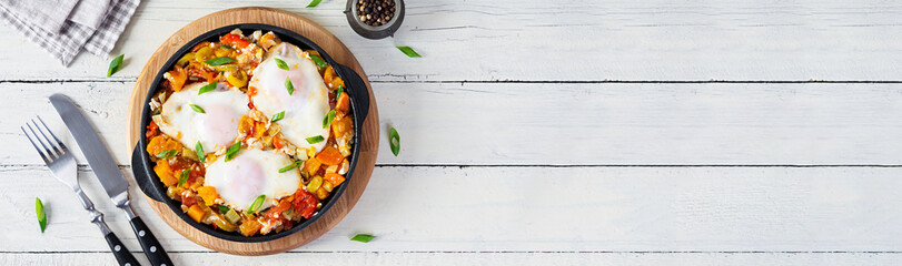 Shakshouka in frying pan. Fried eggs with vegetables, tomato, pepper, pumpkin and onion. Top view