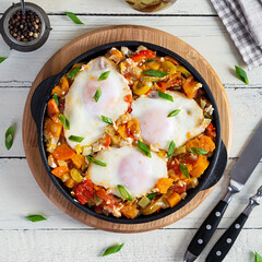 Shakshouka in frying pan. Fried eggs with vegetables, tomato, pepper, pumpkin and onion. Top view