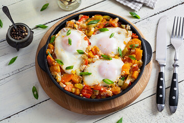 Shakshouka in frying pan. Fried eggs with vegetables, tomato, pepper, pumpkin and onion